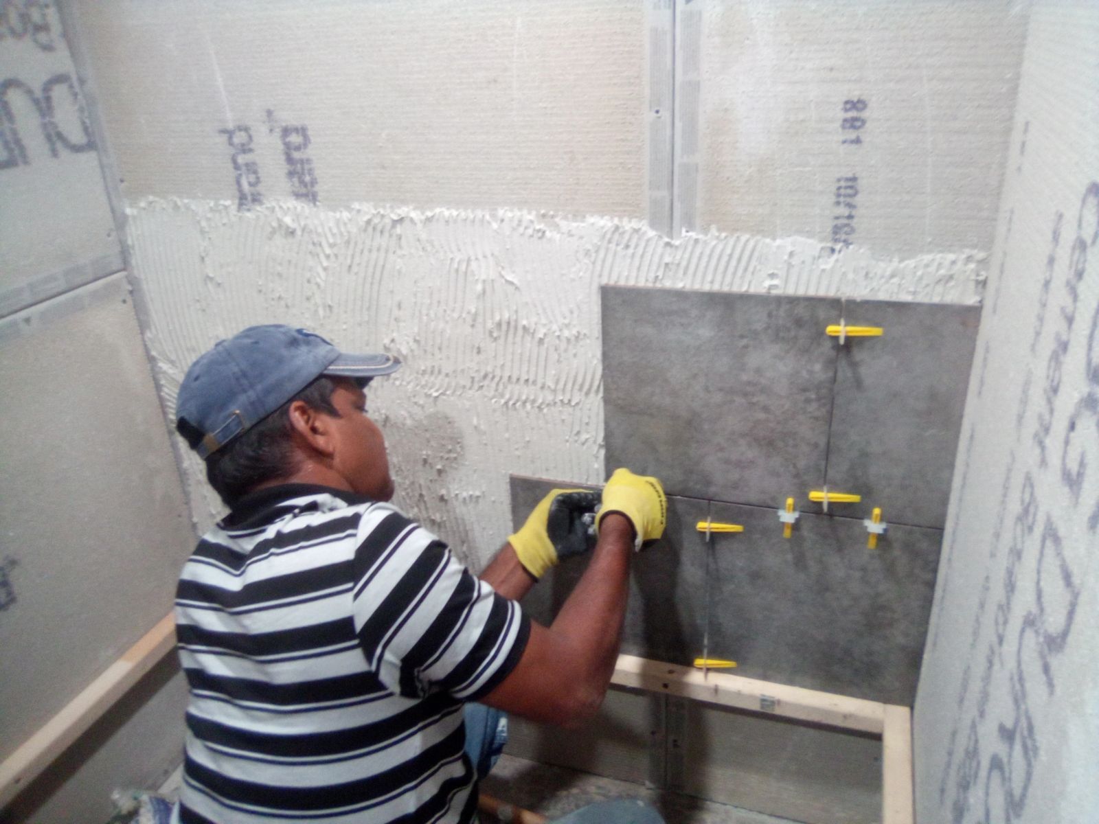 Carpenter setting wall tile over cement board