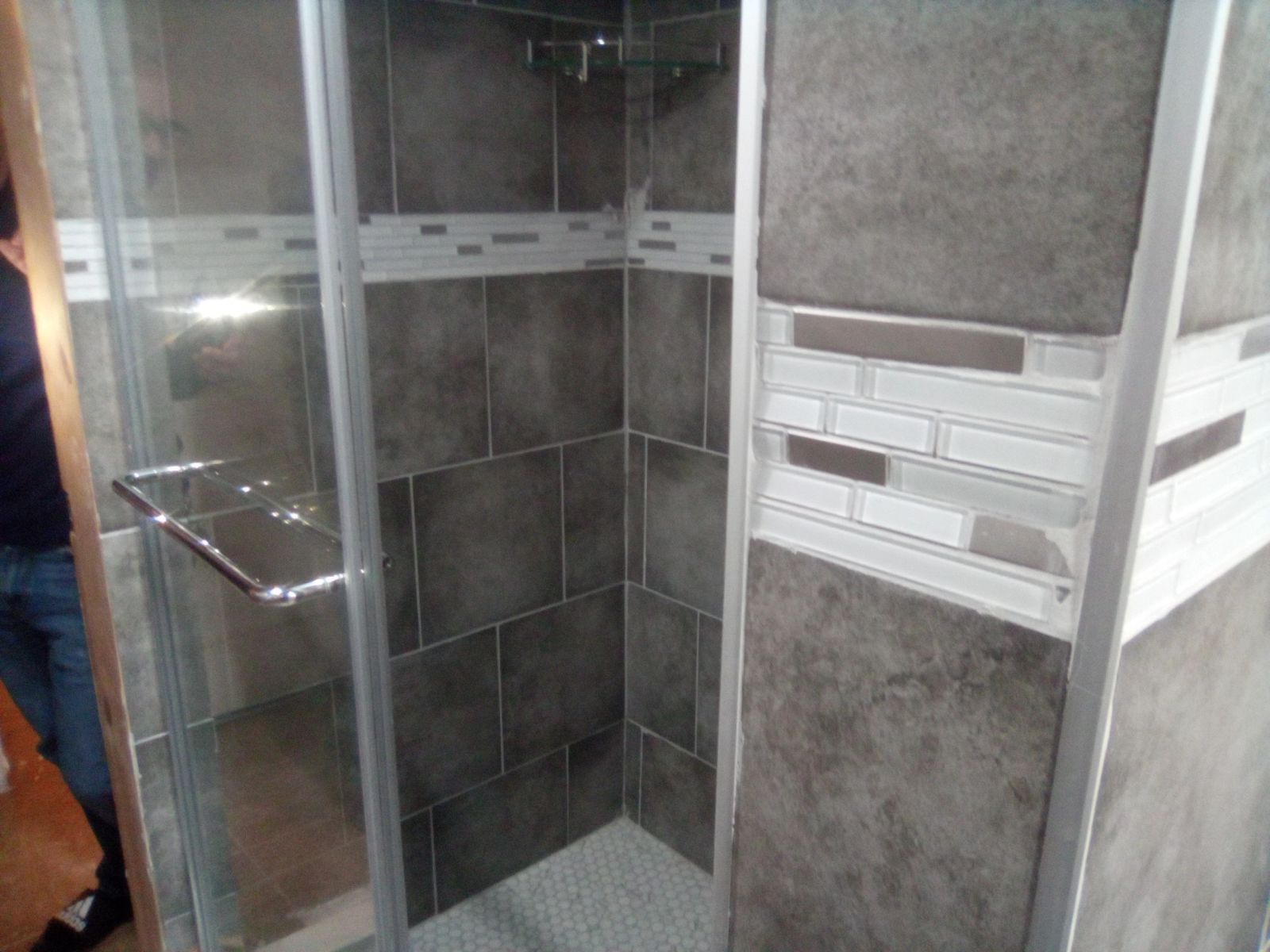 Finished tiled shower with glass door and mosaic accent band