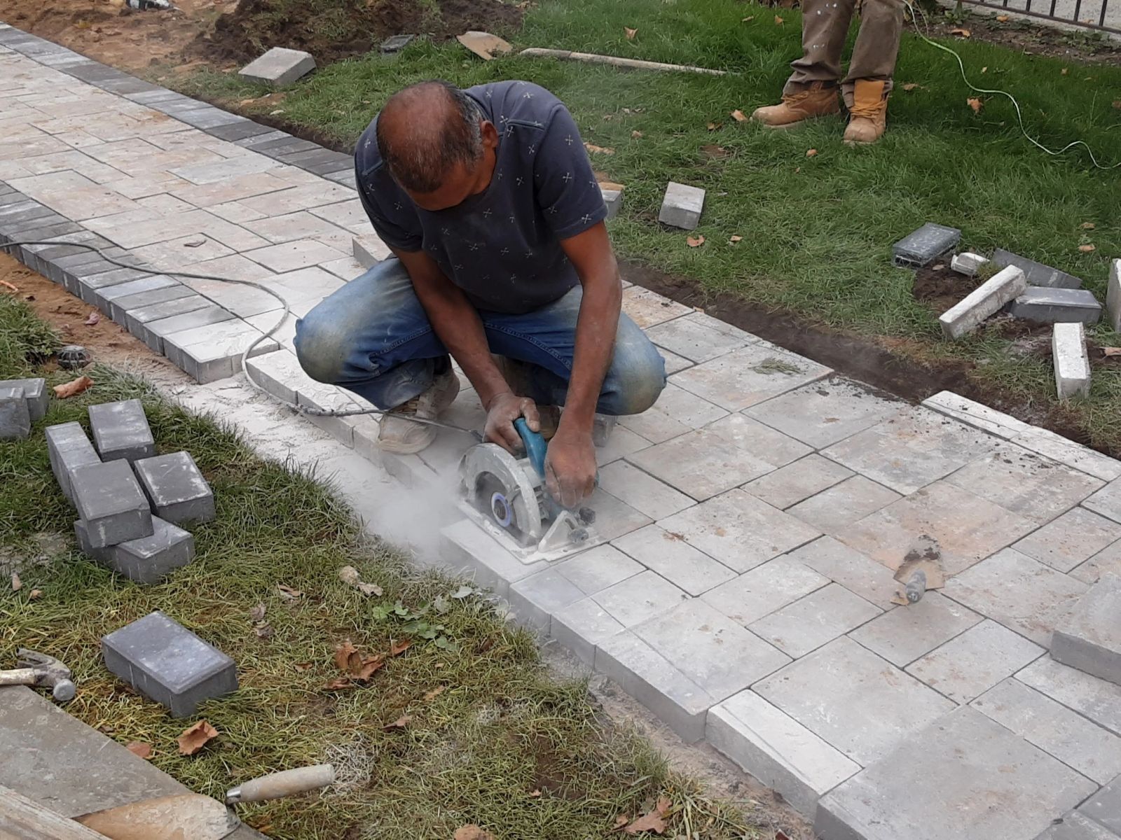 Mason cutting paver stones for a new walkway